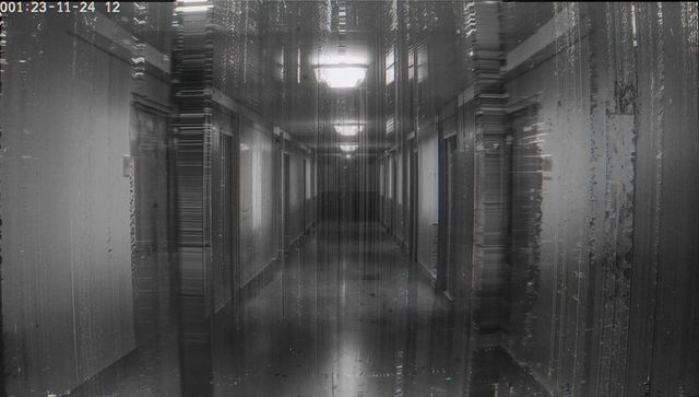 Glitching cctv corridor showing timestamped monochrome hotel hallway with light streaks