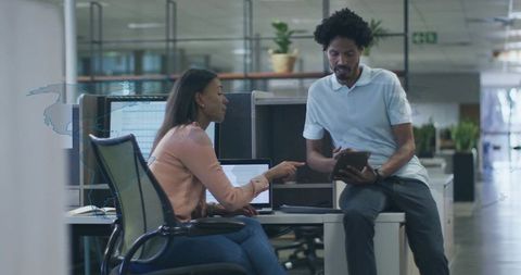 Office colleagues collaborating over tablet in open workspace