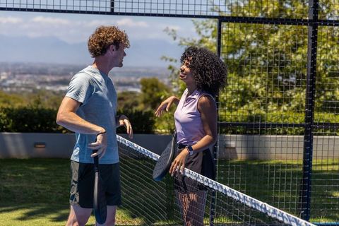 Young players chatting over net on outdoor paddle court during sunny friendly pickleball