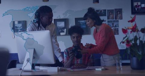 Creative team reviewing dslr in modern office with world map graphic