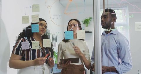 Collaborative Team Brainstorming with Sticky Notes on Glass Board