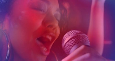 Energetic singer performing on club stage with colorful lights