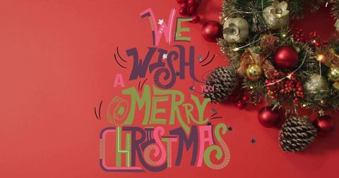 Hand-lettered merry christmas typography on red backdrop with festive wreath and ornaments