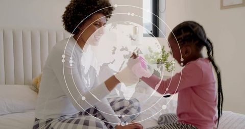 Mother and child playing on bed with globe overlay representing global bonding