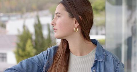 Contemplative woman on balcony overlooking urban scene