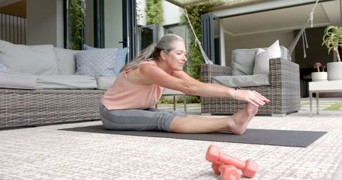 Mature Woman Stretching on Outdoor Yoga Mat Surrounded by Nature