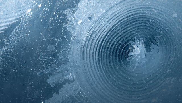 Concentric ice rings spiraling around central crystal spike macro frost pattern close-up