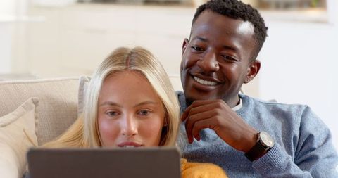 Diverse Couple Relaxing Together with Laptop at Home