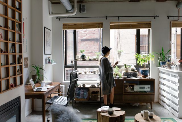 Woman in Cozy Urban Apartment with Plants and Laptop - Download Free Stock Images Pikwizard.com