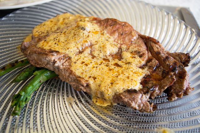 This mouth-watering image of a grilled steak with creamy sauce served on a clear glass plate is perfect for culinary blogs, food product advertisements, restaurant menus, and gourmet recipe books. Its appetizing presentation highlights high-quality dining, making it ideal for promotions of fine dining restaurants or special occasions.