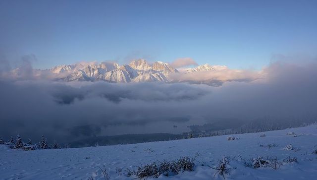 Glowing Snow-Capped Mountain Range Emerging Above Fog-Filled Alpine Valley at Dawn
