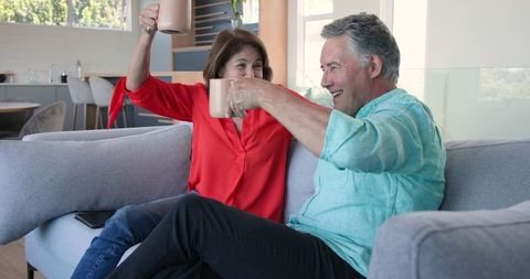 Senior couple joyfully enjoying coffee and togetherness on sofa