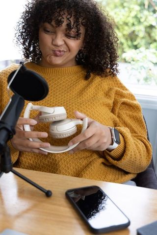 African american woman testing over-ear headphones during home podcast recording session