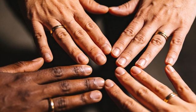 Diverse adult hands forming loose circle displaying gold wedding bands closeup