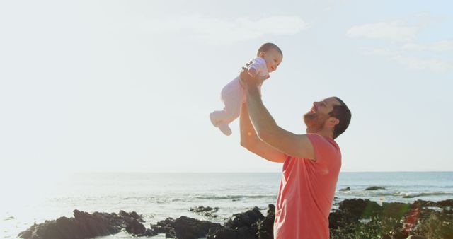 Father lifting baby outdoors near rocky beach - Download Free Stock Images Pikwizard.com