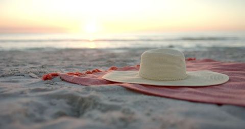 Tranquil Sunset Beach Scene with Sun Hat on Sandy Shores