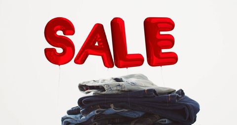 Red balloon sale sign above stack of denim pants