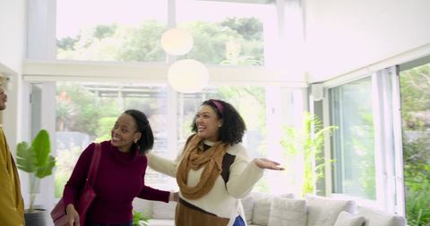 Sunlit modern living room friends greeting and laughing during casual home visit