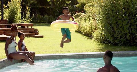 Energetic boy jumping into pool with inflatable, enjoying summer fun