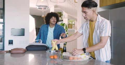Diverse male friends engaging over fresh produce in modern kitchen
