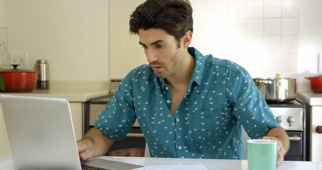 Young Man Using Laptop in Kitchen with Coffee Mug - Download Free Stock Images Pikwizard.com