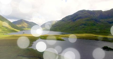 Serene Mountain Lake with Green Hills and Sunlight Bokeh