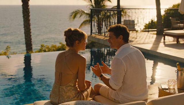 Couple enjoying sunset at infinity pool with ocean view and champagne on tropical terrace