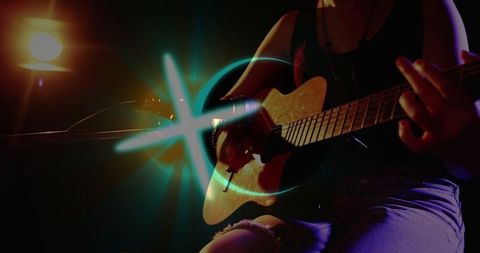 Musician Playing Acoustic Guitar on Stage with Dramatic Lighting
