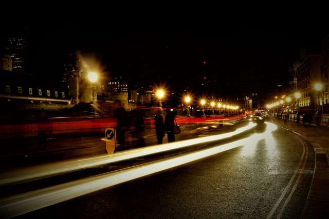 Image captures the dynamic light trails of night traffic on a city street using long exposure. Street lamps illuminate the scene, highlighting the movement of cars and creating a vibrant urban atmosphere. Good for presentations on urban life, traffic analysis, and creating energetic city-themed backgrounds.