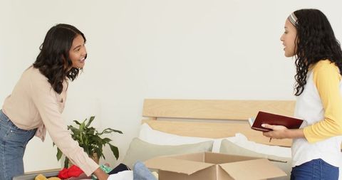 Women organizing closet in modern bedroom