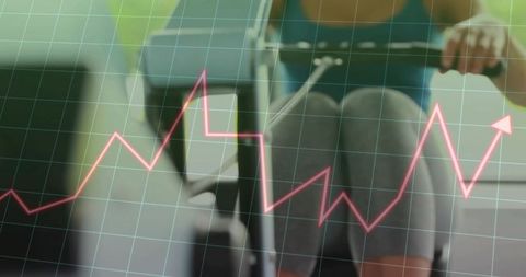 Woman rowing on ergometer showing performance graph, cardio metrics and training progress