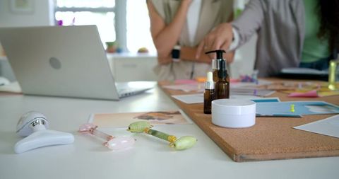 African american women collaborating over skincare product prototypes on studio worktable