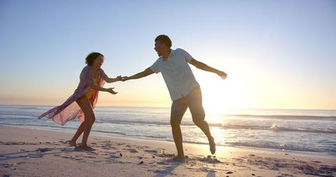 Playful Beach Stroll at Sunset With Happy Couple - Download Free Stock Images Pikwizard.com
