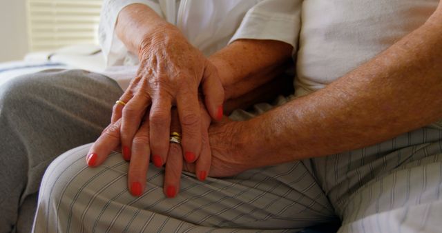 Close-up of senior couple holding hands in bedroom at comfortable home. Mid section of senior couple relaxing on bed 4k