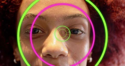 Closeup female face gazing through neon concentric rings, red curly hair, silver hoops
