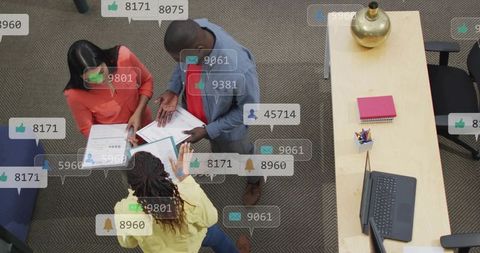 Overhead view of diverse team discussing documents and tablet in modern collaborative office workspa