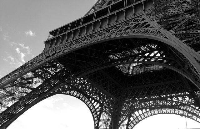 This stock photo highlights the intricate iron structure of the Eiffel Tower in Paris, captured in captivating black and white. It emphasizes detailed craftsmanship and architectural beauty, making it suitable for travel blogs, educational materials on architectural design, historical articles, or as inspirational imagery for creative projects.