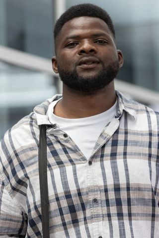 Confident african american man standing outdoors by glass building wearing plaid shirt