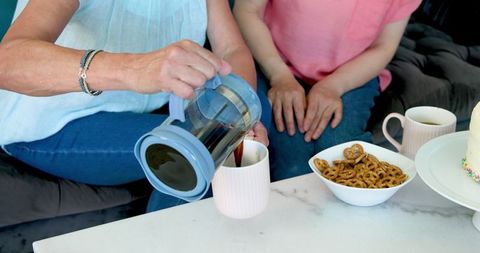 Senior friends enjoying coffee and pretzels at home gathering