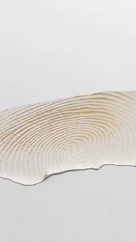 Vertical studio video filming translucent spiral-ridge strip resembling fingerprint texture