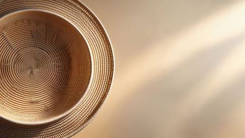 Rustic Round Woven Straw Basket on Sunlit Beige Surface