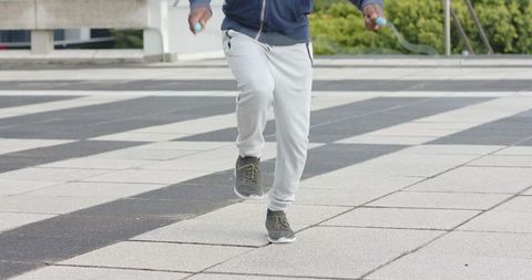Mature African American Male Jumping Rope on Urban Plaza in Grey Sweatpants and Sneakers