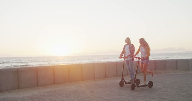 Young Women Riding Electric Scooters Along Sunset Beach Path - Download Free Stock Images Pikwizard.com