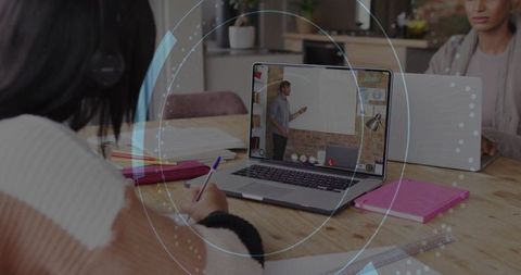 Teenagers taking online lessons and writing notes at home