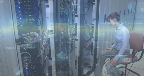 Female IT professional leaning, inspecting server racks and network cabling in data center