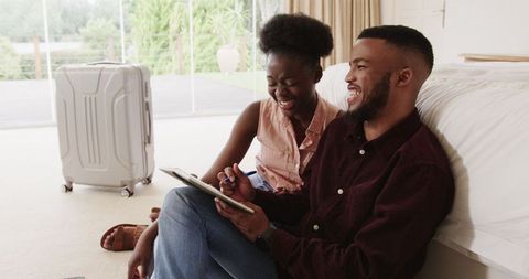 Happy couple planning travel at home using tablet and pen