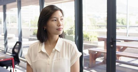 Thoughtful Asian Woman in Modern Office With Bright Lighting