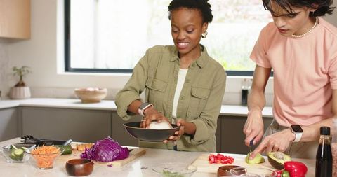 Couple Preparing Healthy Meal Mixing Salad and Slicing Avocado in Contemporary Kitchen