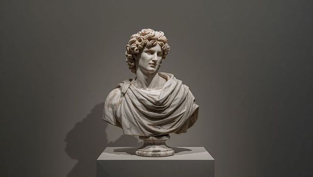 Classical marble bust on pedestal in museum spotlight