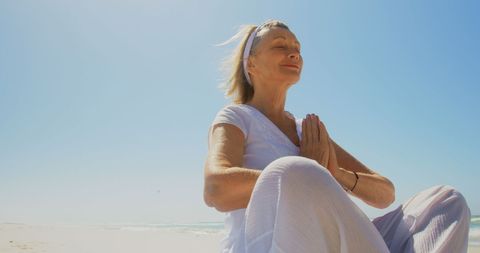 Senior Woman Meditating Peacefully on Sandy Beach